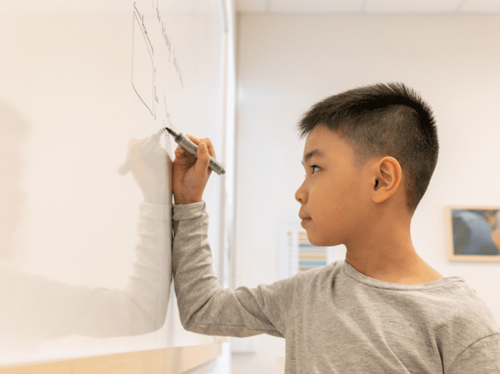 Boy solving maths sums on the whiteboard